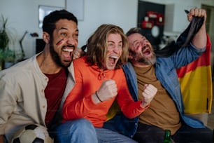 Des amis heureux fans de football allemands regardent un football à la maison et célèbrent.