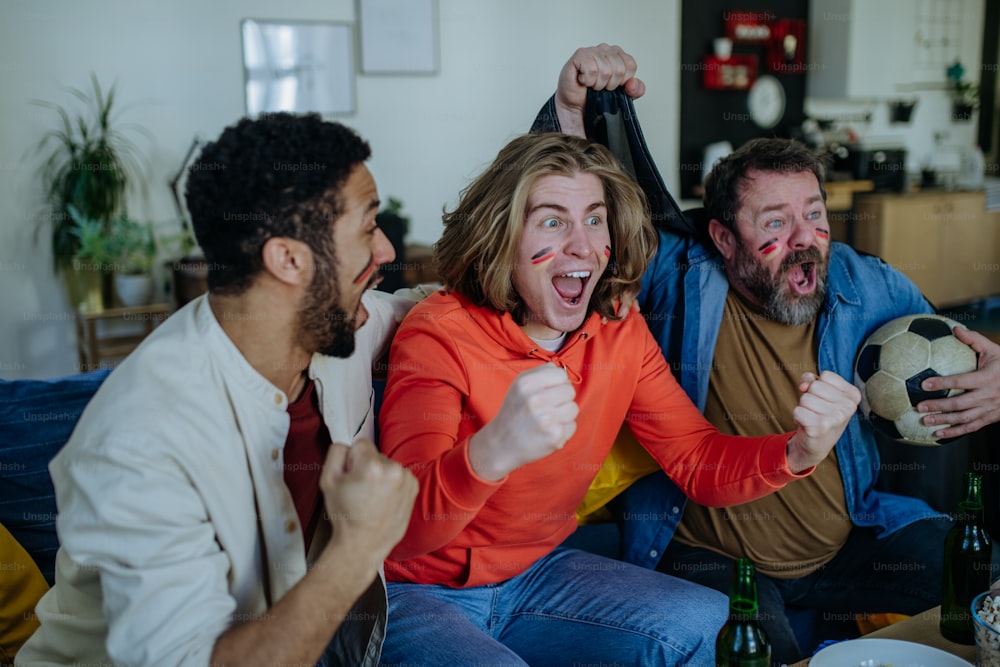 Amici felici tifosi di calcio tedeschi che guardano il calcio a casa e celebrano il successo