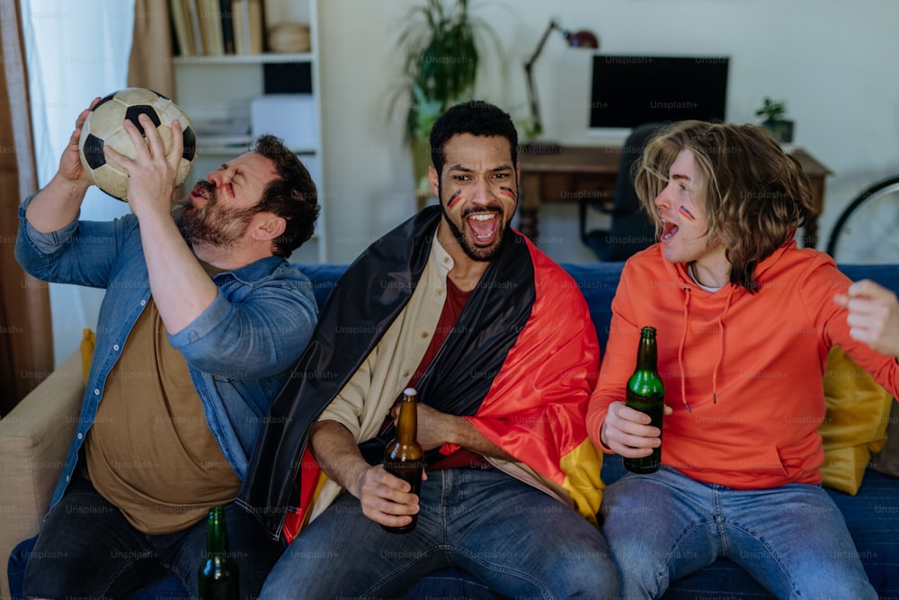 Felices amigos de los aficionados al fútbol alemán viendo el fútbol en casa y celebrando el éxito