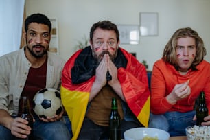 Nervöse Fußballfans, Freunde, die auf den Fernseher starren und zu Hause Fußballspiele schauen.