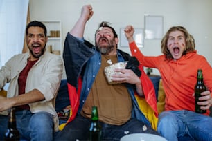 Felizes fãs de futebol alemães amigos assistindo futebol em casa e comemorando o sucesso
