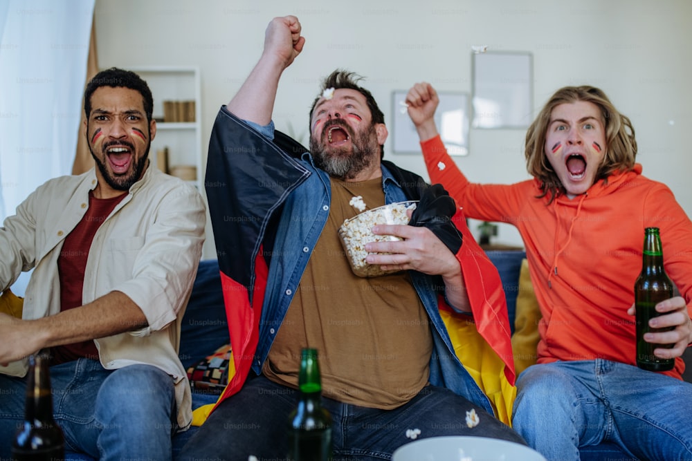 Felices amigos de los aficionados al fútbol alemán viendo el fútbol en casa y celebrando el éxito