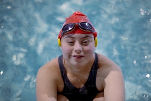 Eine junge Frau mit Down-Syndrom schwimmt im Schwimmbad und schaut in die Kamera