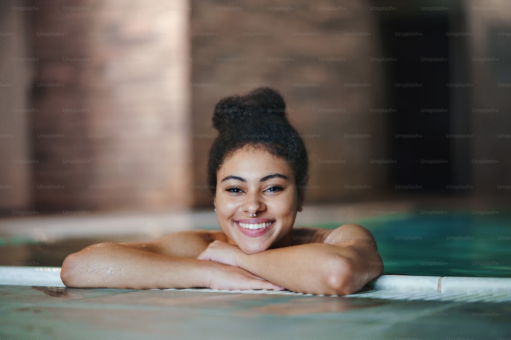 Portrait of happy young woman in indoor swimming pool, looking at camera.