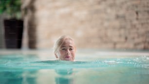 Retrato de una mujer mayor feliz en piscina cubierta, natación.