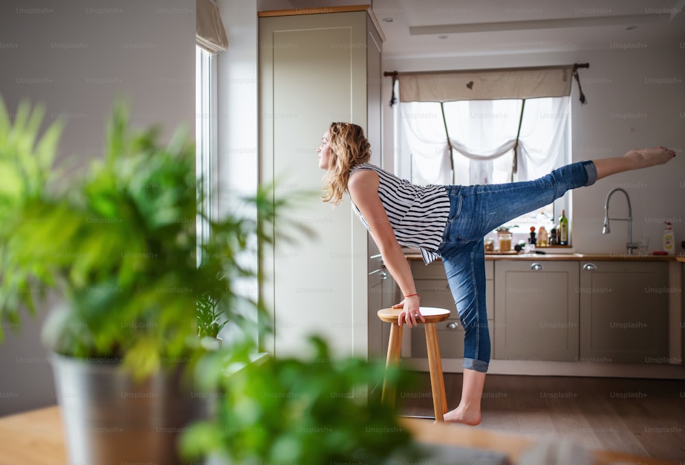 Giovane donna che si rilassa in casa in cucina a casa, stretching.