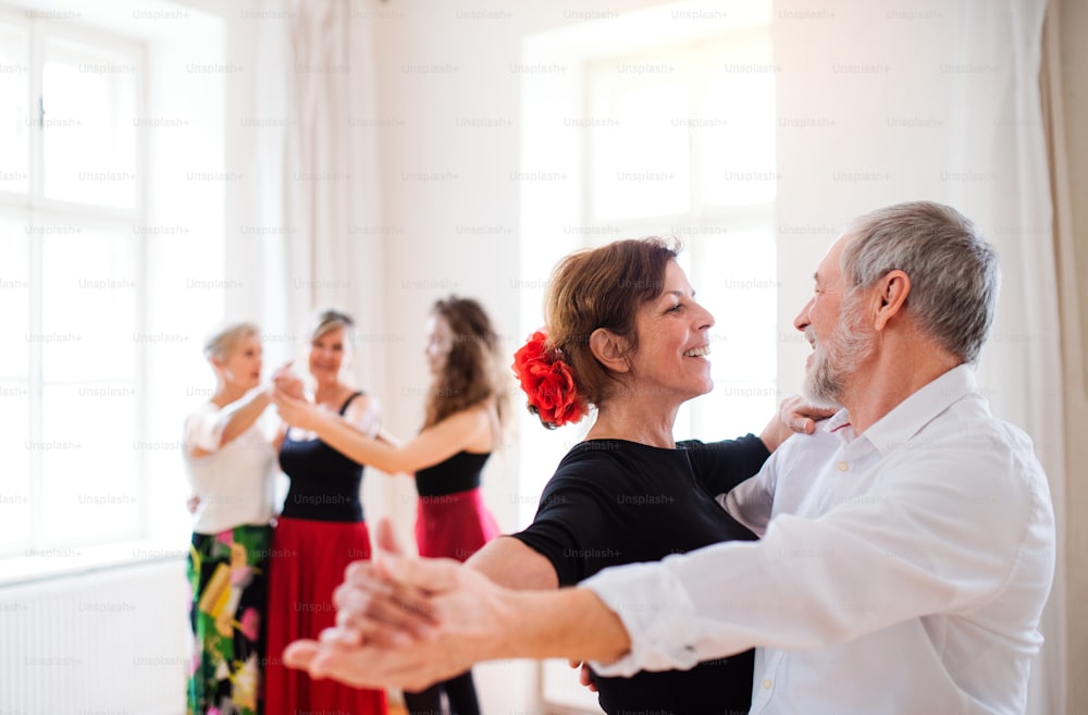 Eine Gruppe älterer Leute, die mit einem jungen Tanzlehrer einen Tanzkurs besuchen.
