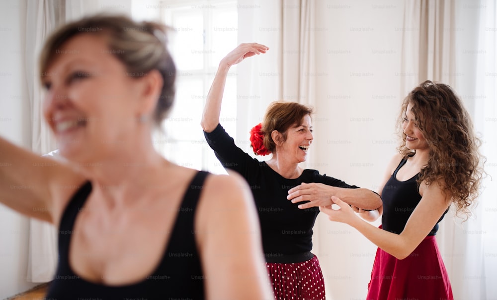 Un grupo de mujeres mayores asistiendo a clase de baile con profesor de baile.