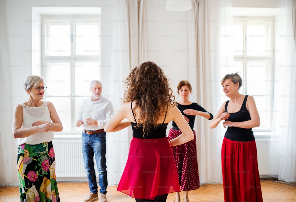 Un gruppo di persone anziane che frequentano lezioni di danza con insegnante di danza.