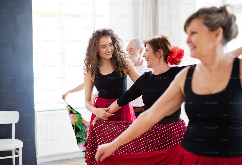 Un grupo de personas mayores asistiendo a clase de baile con profesor de baile.