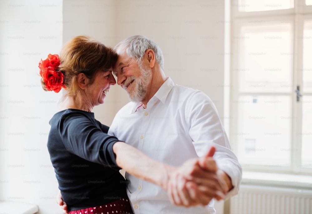 Happy senior couple in love attending dancing class in community center.