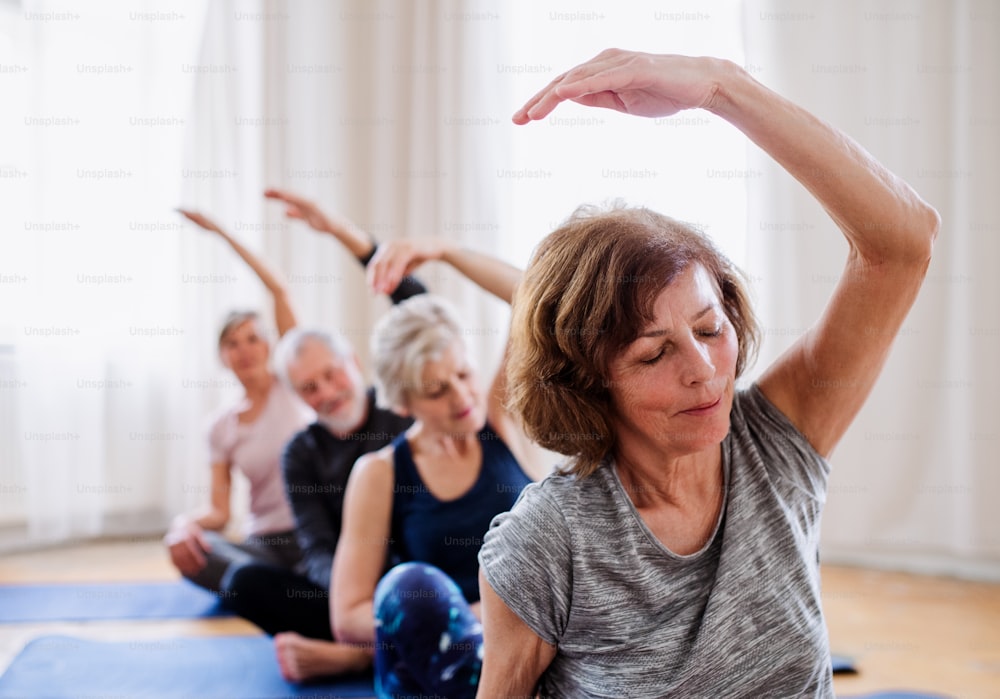 Gruppo di persone anziane attive che fanno esercizi di yoga nel club del centro della comunità.
