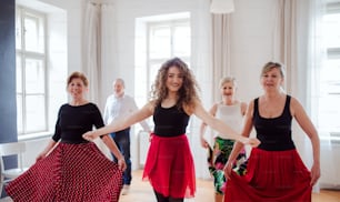 A group of senior people attending dancing class with dance teacher.