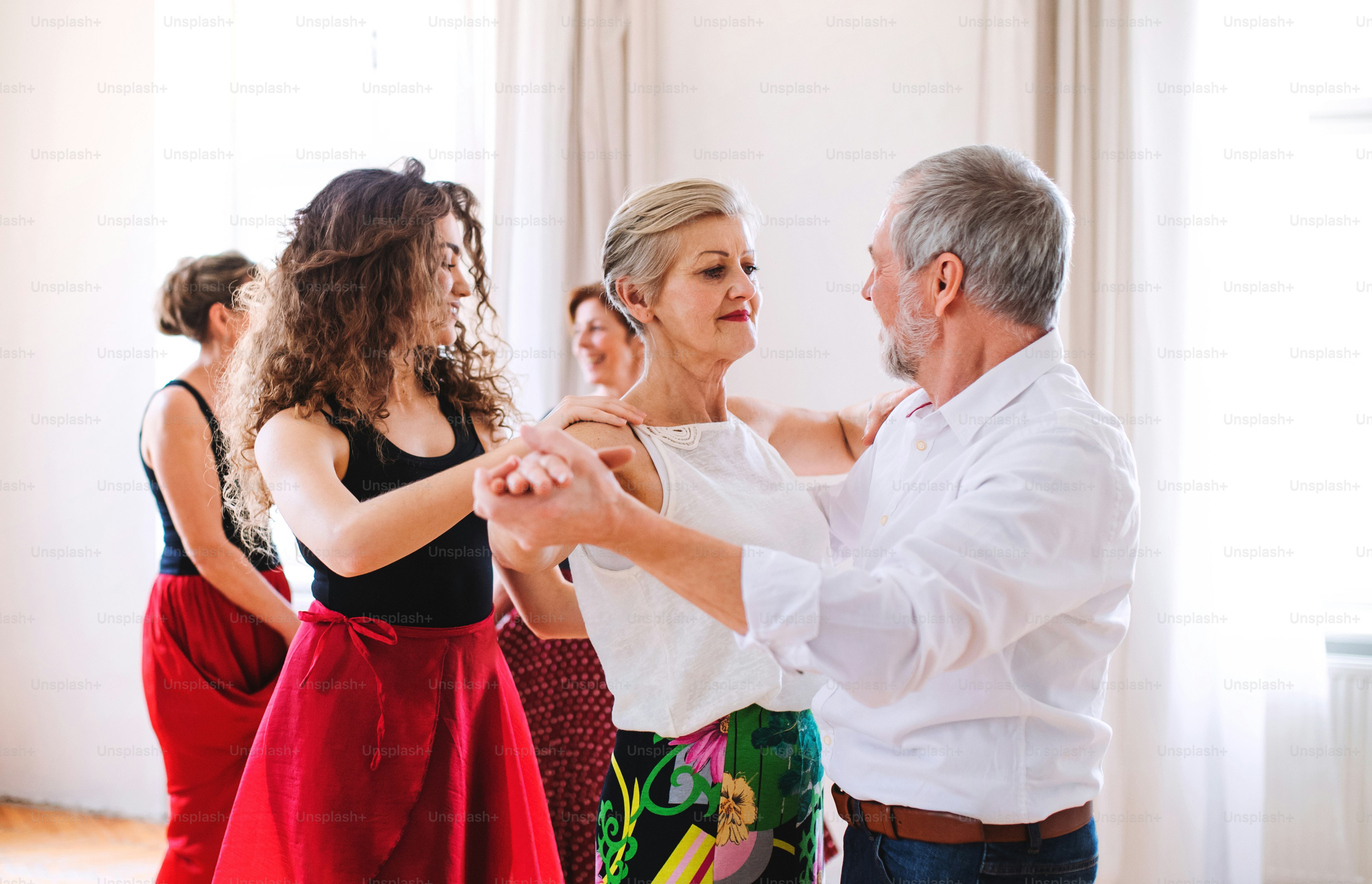 A group of senior people attending dancing class with dance teacher.