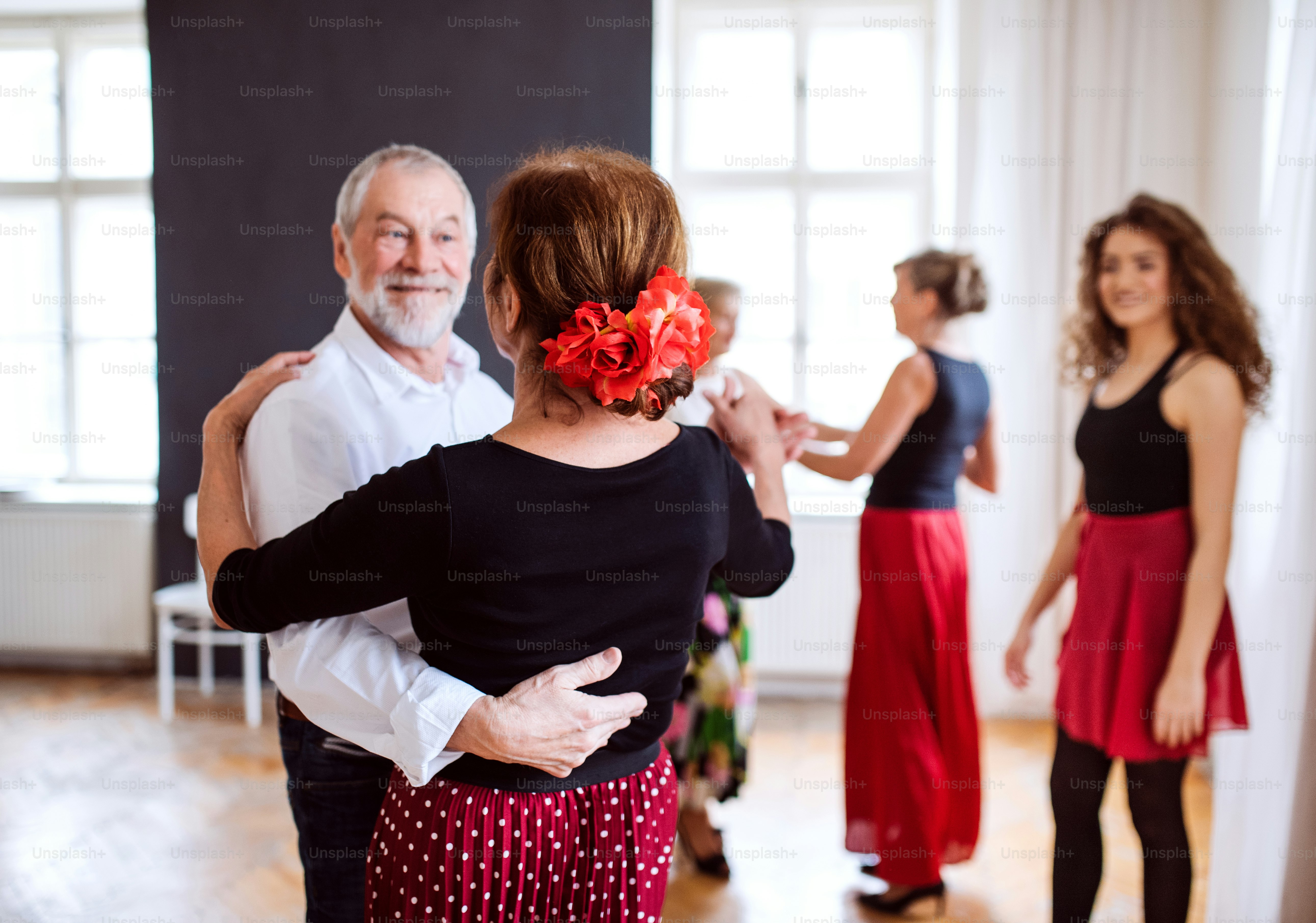 A group of senior people attending dancing class with dance teacher.