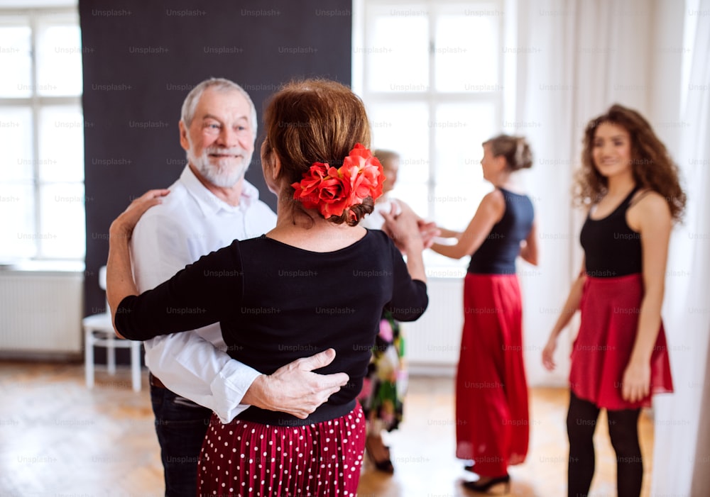 A group of senior people attending dancing class with dance teacher.