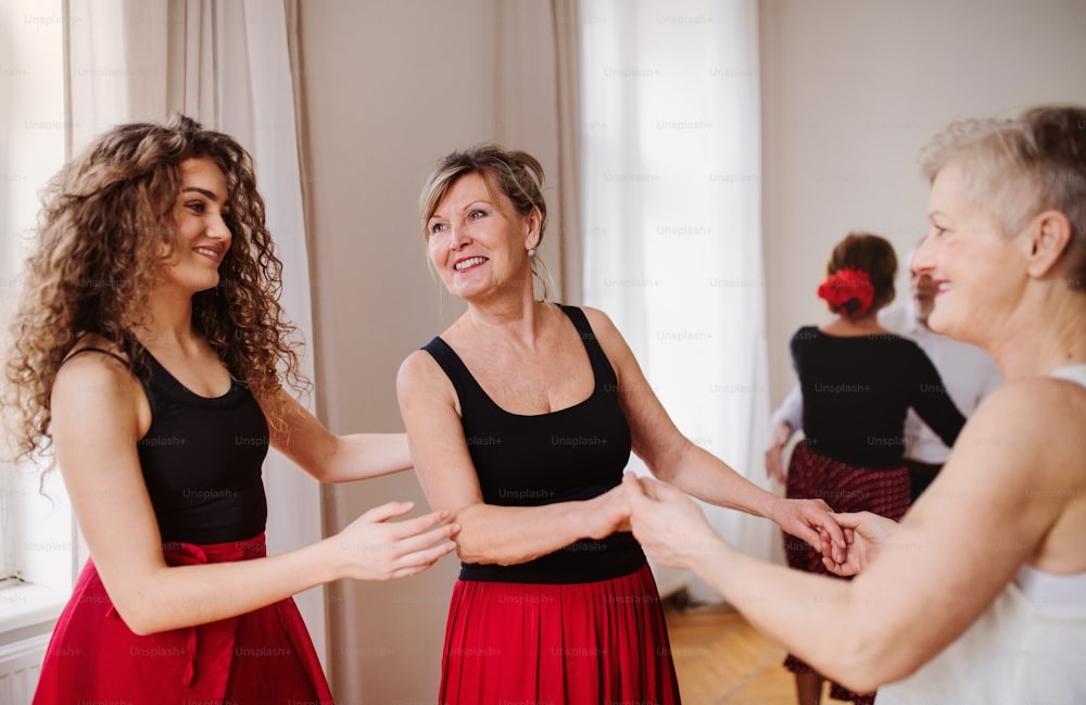 A group of senior people attending dancing class with dance teacher.