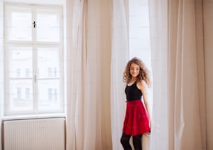 Un retrato de una joven profesora de danza en el interior de pie junto a la ventana. Espacio de copia.