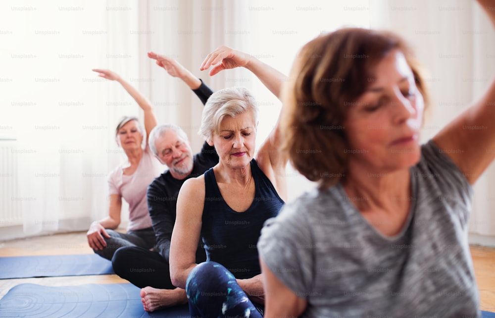 Grupo de personas mayores activas haciendo ejercicio de yoga en el club del centro comunitario.