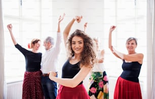 A group of senior people attending dancing class with dance teacher.