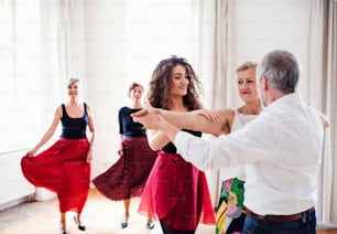 Eine Gruppe älterer Leute, die mit einem jungen Tanzlehrer einen Tanzkurs besuchen.