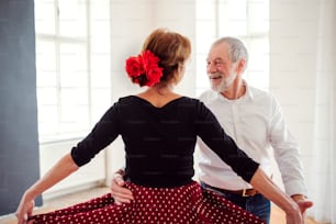 Happy senior couple in love attending dancing class in community center.