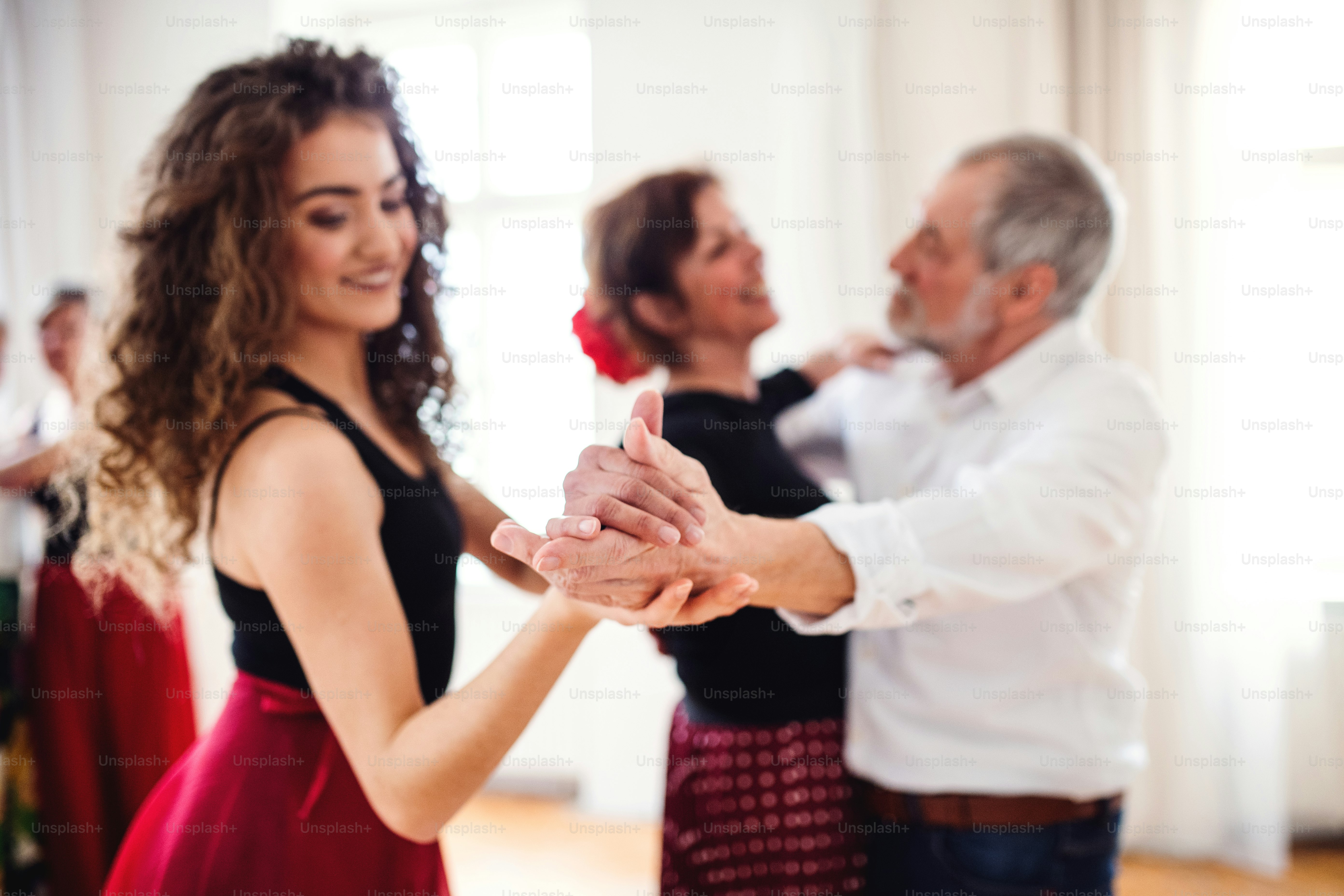 A group of senior people attending dancing class with dance teacher.