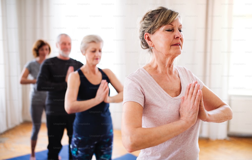 Grupo de personas mayores activas haciendo ejercicio de yoga en el club del centro comunitario.