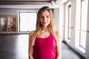 A front view portrait of beautiful young girl or woman in a gym. Copy space.