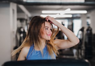A portrait of a beautiful young girl or woman doing cardio workout in a gym.