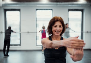A cheerful senior woman in gym doing exercise. Copy space.