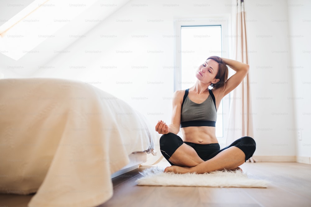 Una giovane donna felice che fa esercizio fisico al chiuso in una camera da letto. Copia spazio.