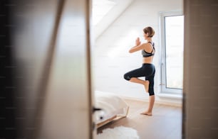 A side view of young woman doing exercise indoors in a bedroom. Copy space.