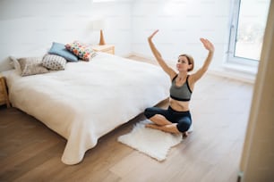 A happy young woman doing exercise indoors in a bedroom. Copy space.