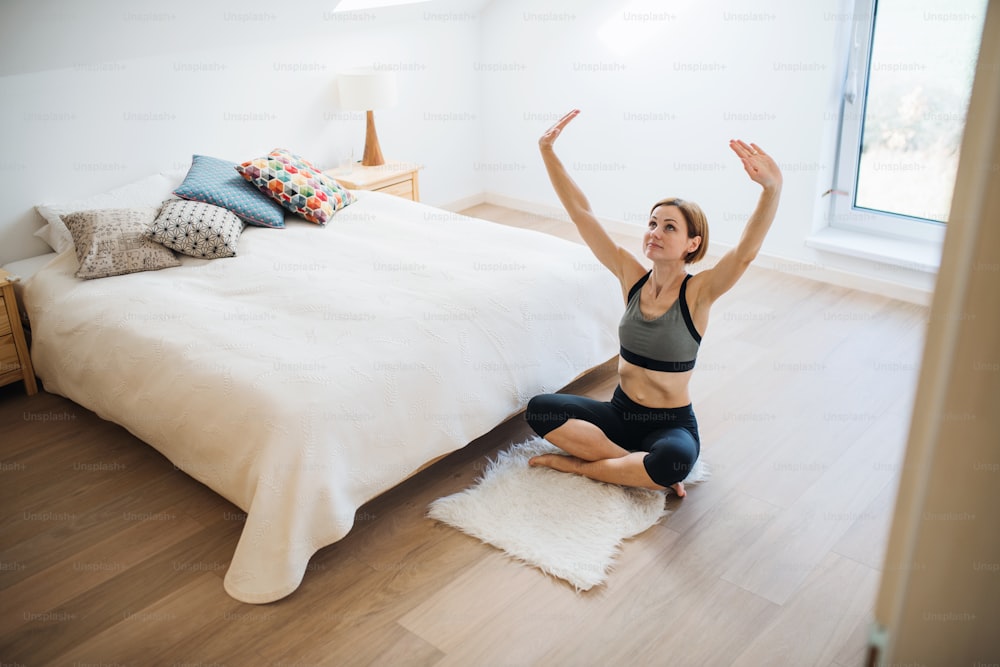 A happy young woman doing exercise indoors in a bedroom. Copy space.