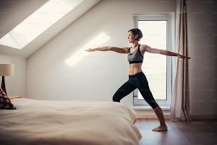 A side view of young woman doing exercise indoors in a bedroom. Copy space.