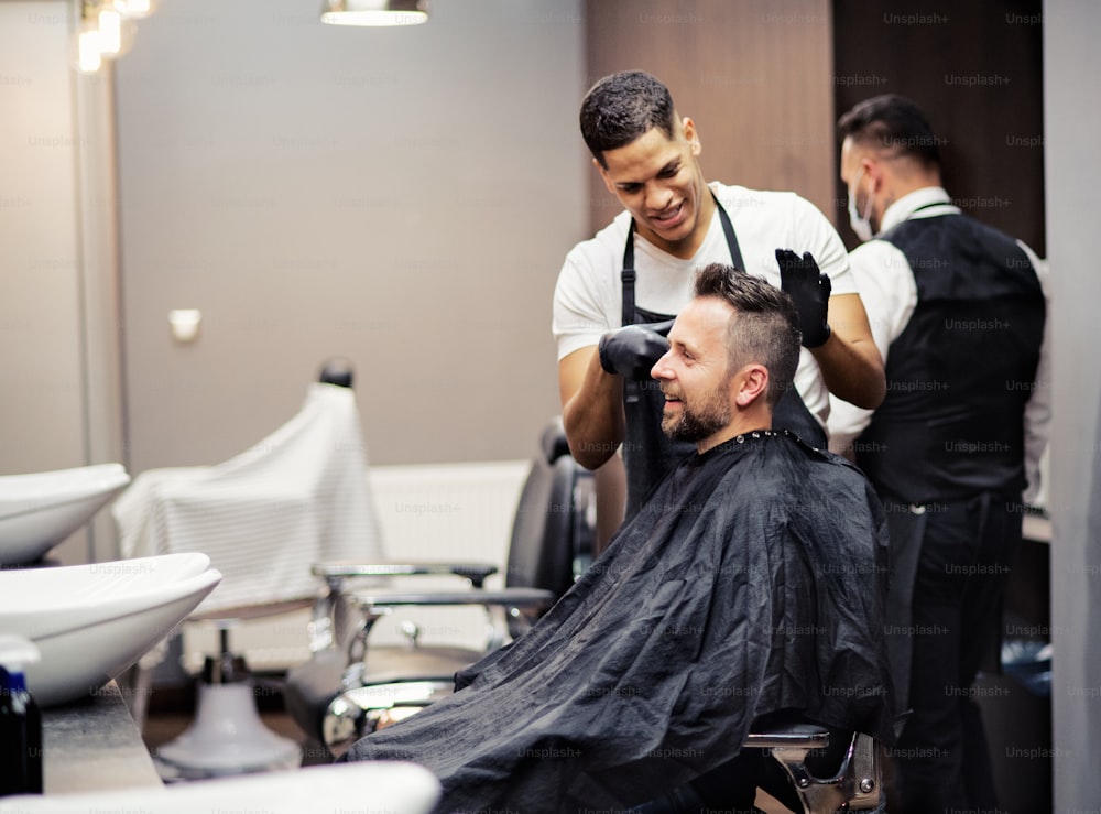 Um cliente hipster que visita haidresser e cabeleireiro em barbearia.