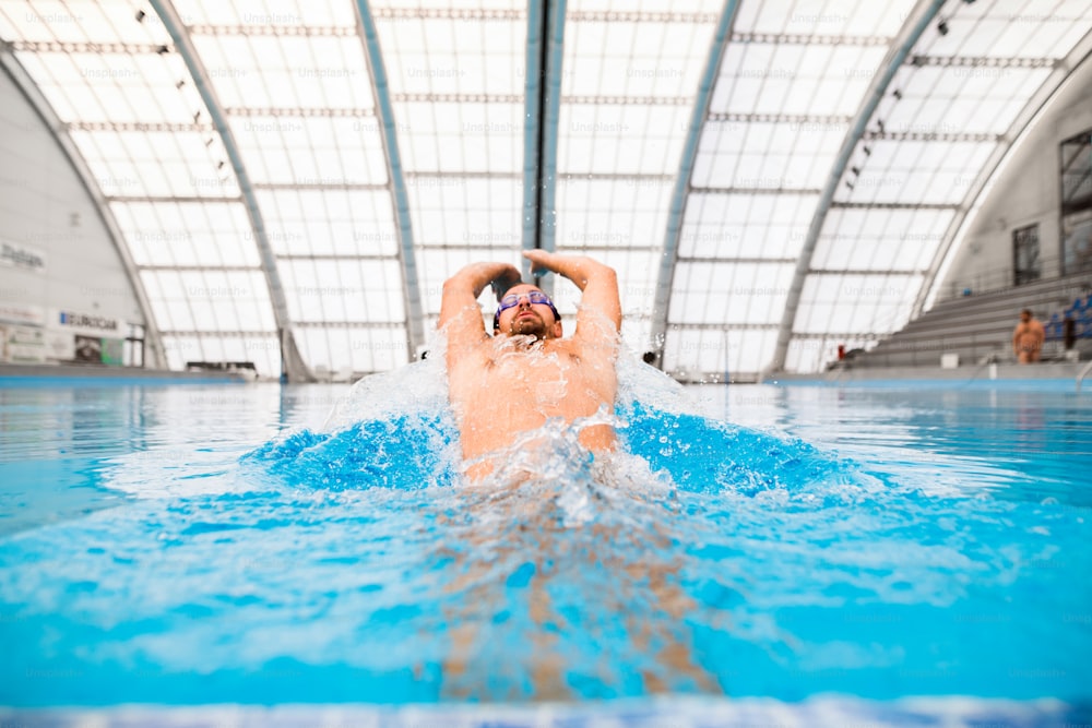 Mann schwimmt in einem Hallenbad. Professioneller Schwimmer beim Üben im Pool.