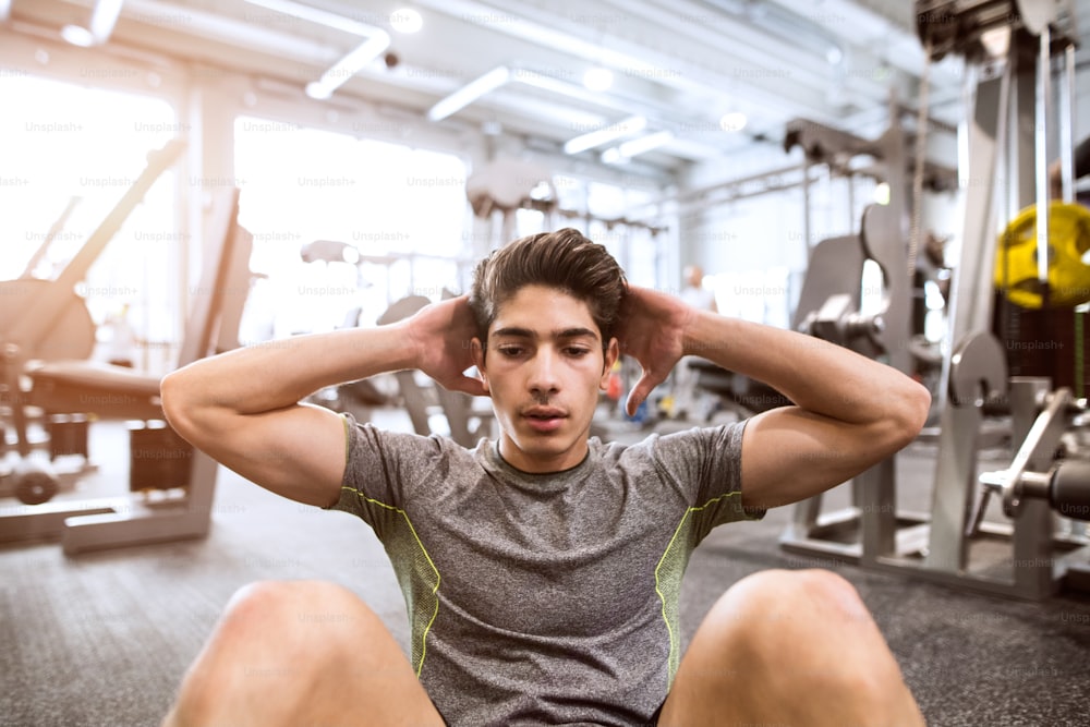 Fit hispanic man at abdominal crunch muscles exercises during training in fitness gym