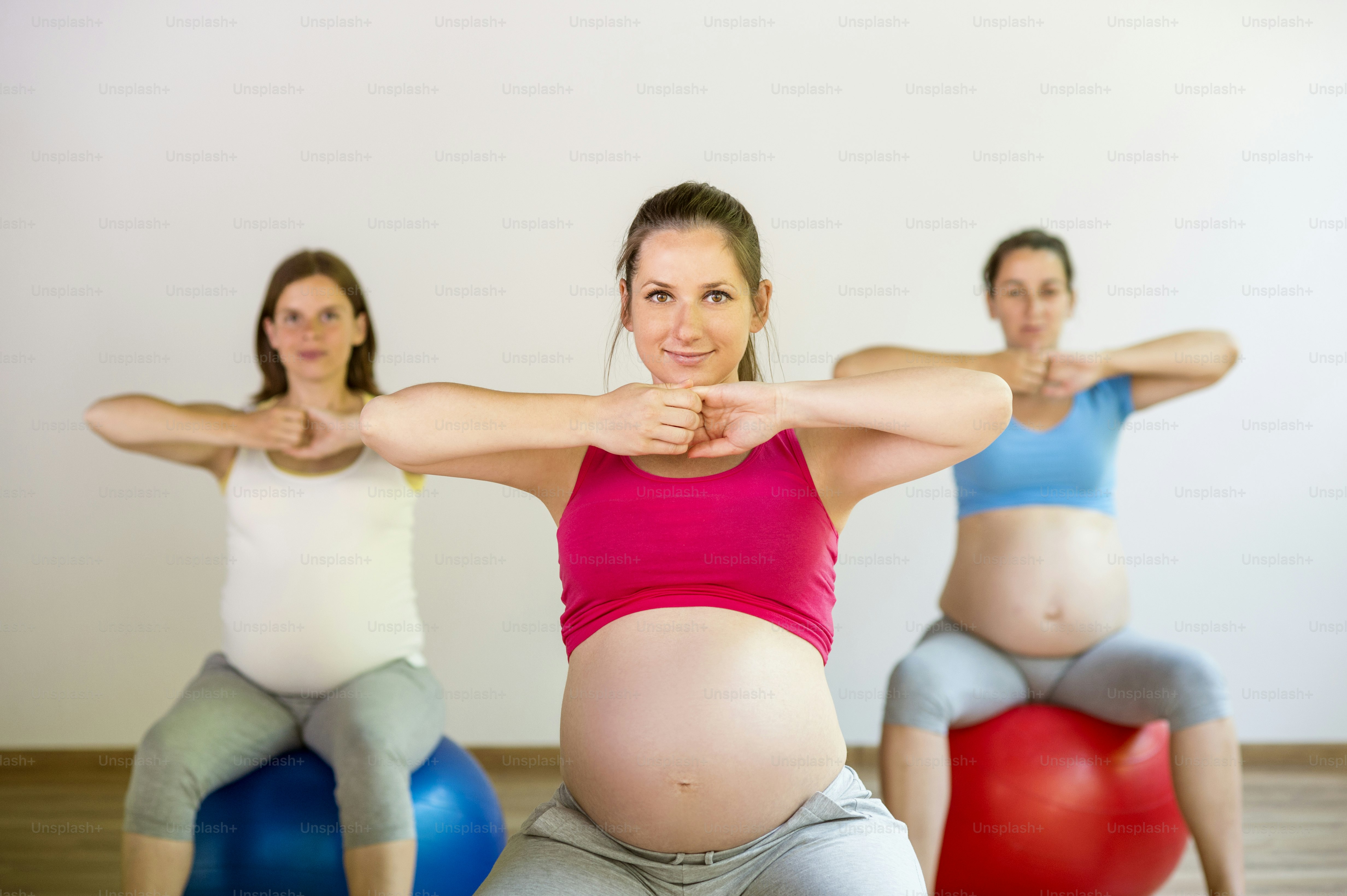 Young pregnant women doing exercise using a fitness ball