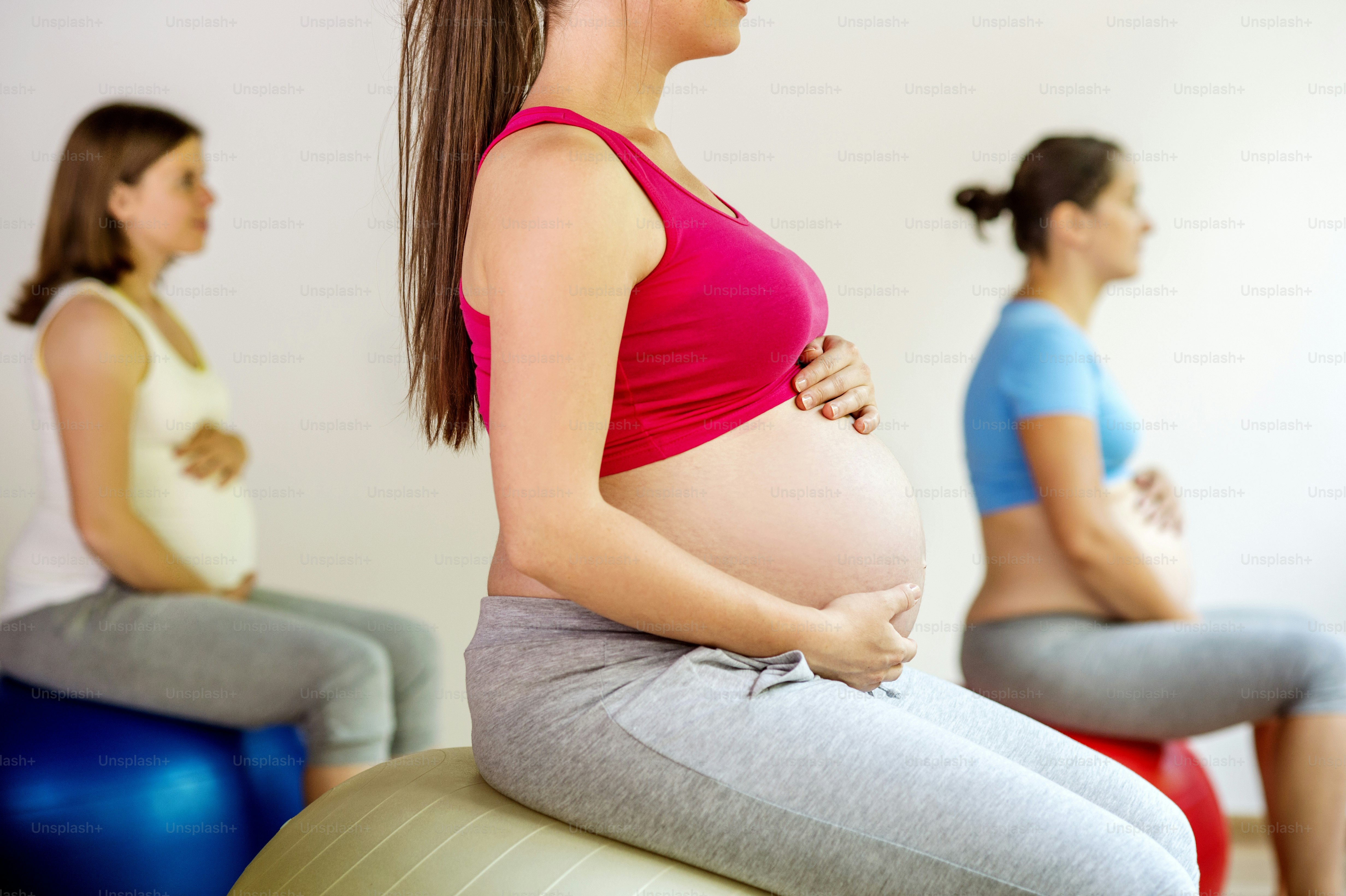 Young pregnant women doing exercise using a fitness ball