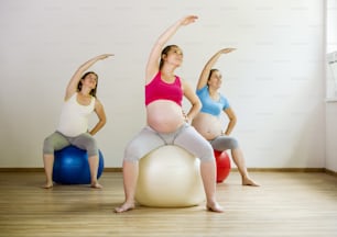 Mujeres embarazadas jóvenes haciendo ejercicio con una pelota de fitness