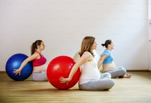 Jeunes femmes enceintes faisant de l’exercice de relaxation à l’aide d’un ballon de fitness