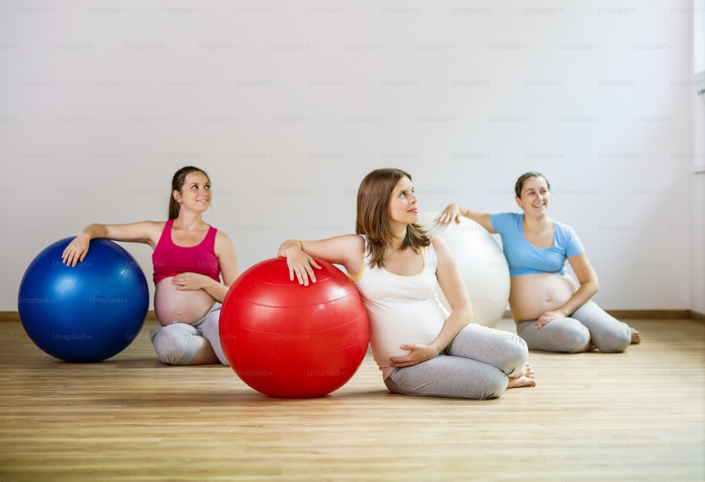 Giovani donne incinte che fanno esercizi di rilassamento usando una palla da fitness