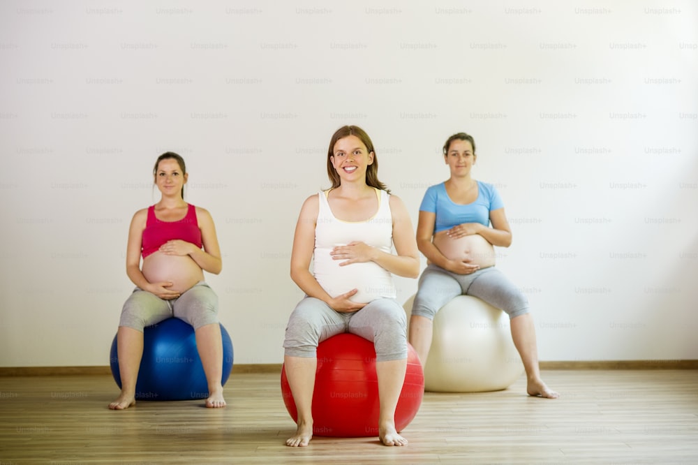 Junge schwangere Frauen, die mit einem Fitnessball trainieren