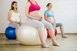 Mulheres grávidas jovens fazendo exercício usando uma bola de fitness