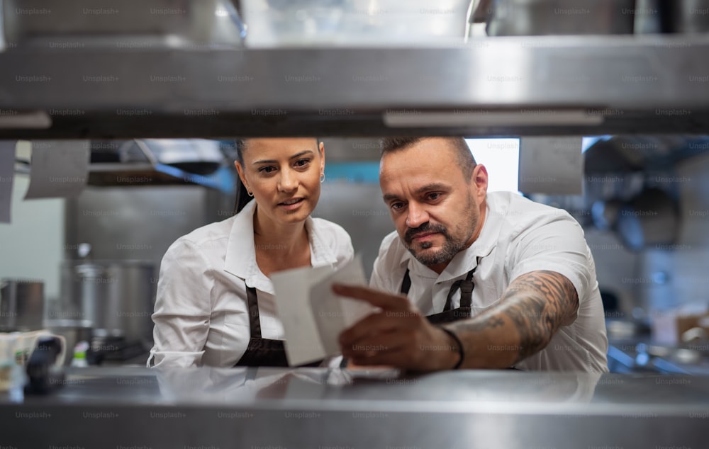A chef and cook taking order slip in commercial kitchen.