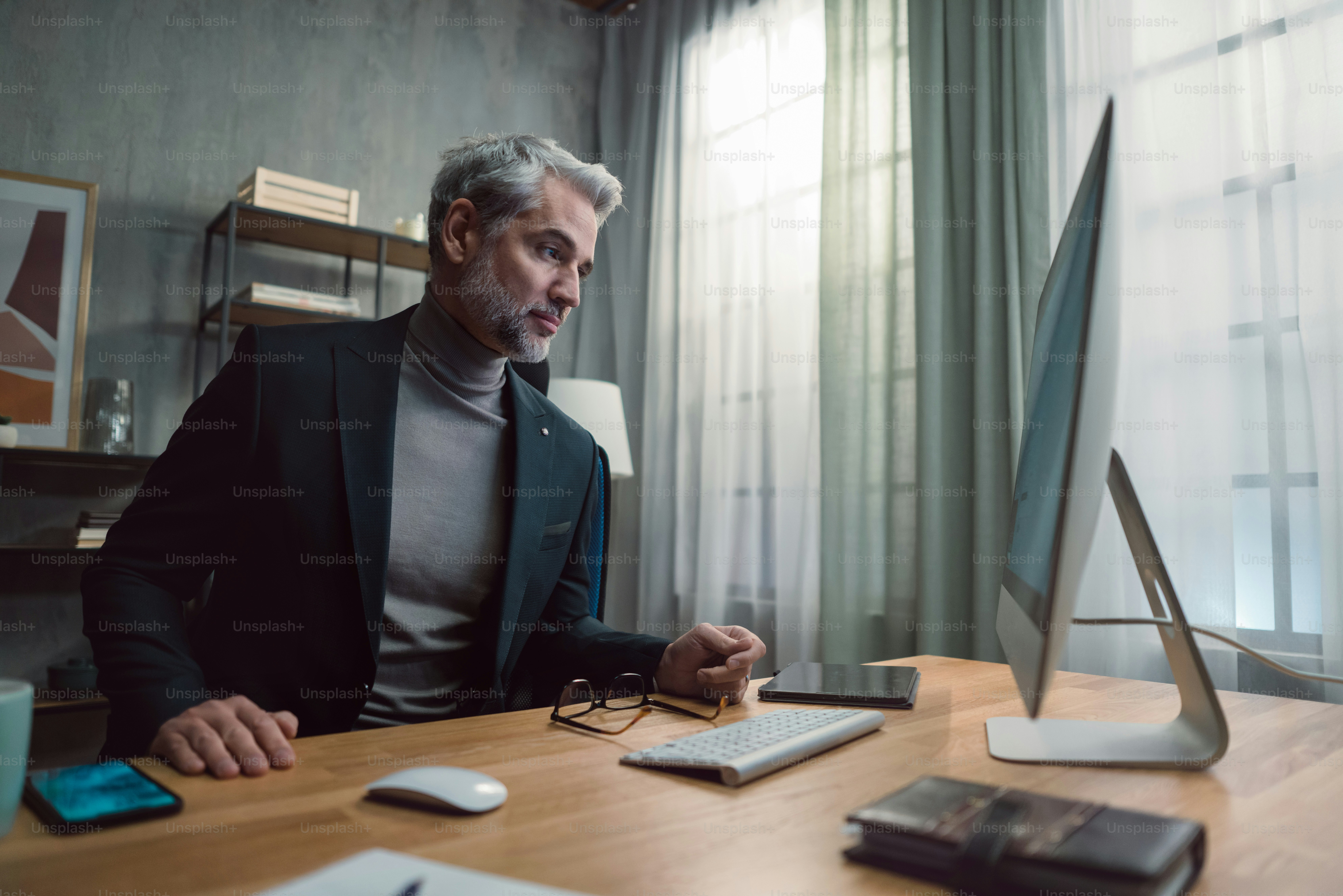 A mature businessman working on computer indoors in office. photo ...