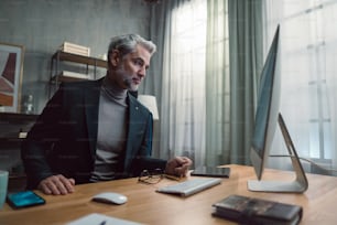 A mature businessman working on computer indoors in office.