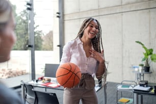 A cheerful young businesswoman having fun with ball in office, take a break concept.